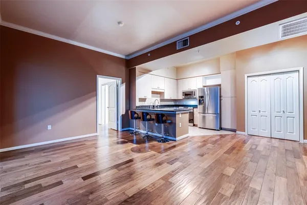 a living room with kitchen view and a wooden floor