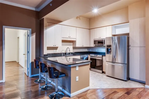 a kitchen with stainless steel appliances granite countertop a refrigerator a sink dishwasher a stove and a refrigerator