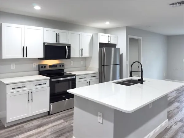a kitchen with a sink a microwave a stove and refrigerator