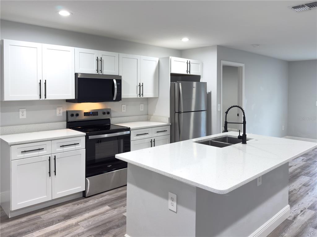 4443 Ferrari Drive Sebring, FL 33872 - Photo 4 of 9 a kitchen with a sink a microwave a stove and refrigerator