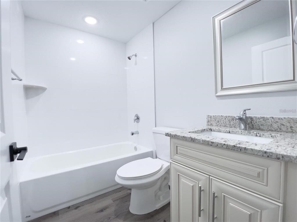 4443 Ferrari Drive Sebring, FL 33872 - Photo 6 of 7 a bathroom with a granite countertop sink toilet a mirror and bathtub