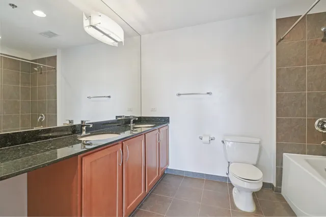 a bathroom with a granite countertop sink a toilet and a mirror