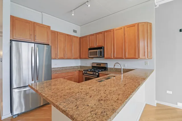 a kitchen with granite countertop a refrigerator a stove top oven cabinets and a sink