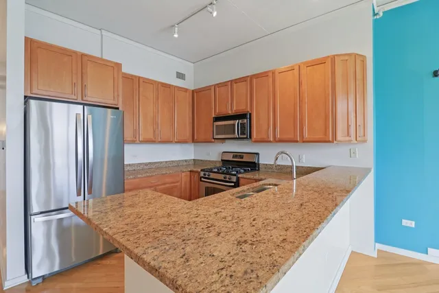 a kitchen with granite countertop a refrigerator a stove top oven cabinets and a sink