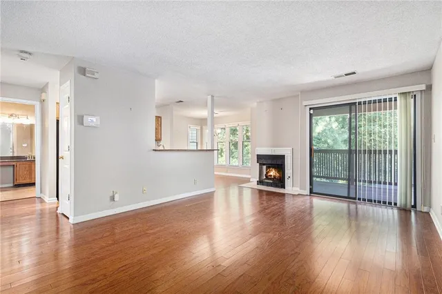 an empty room with wooden floor fireplace and windows