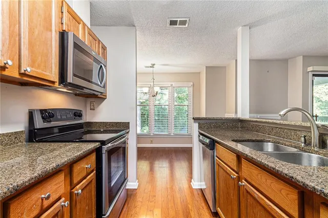 a kitchen with stainless steel appliances granite countertop a sink stove and cabinets