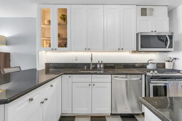 a kitchen with granite countertop a sink stainless steel appliances and cabinets