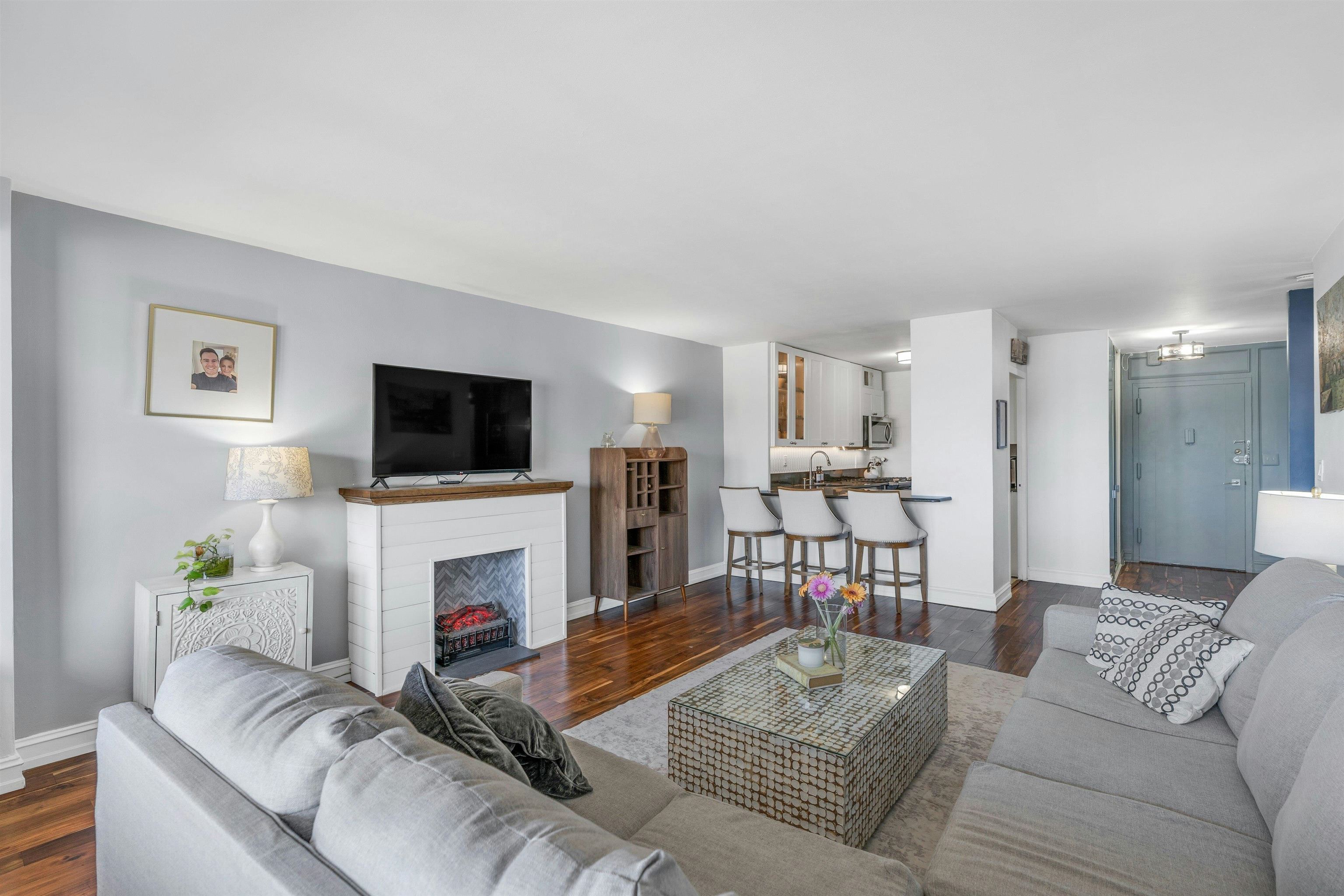 1203 River Road, Unit 9D Edgewater, NJ 07020 - Photo 10 of 28 a living room with furniture a flat screen tv and a fireplace