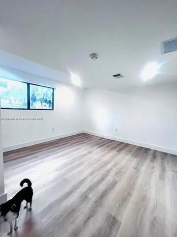 a view of empty room with window and wooden floor