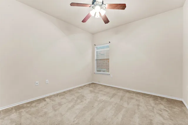 a view of an empty room and chandelier fan
