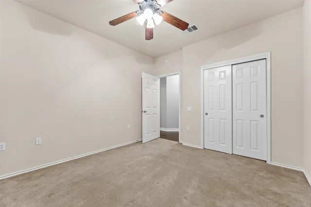 a view of an empty room and chandelier fan