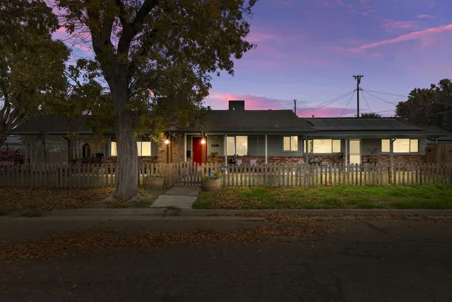 a view of a brick house next to a yard with a big yard and potted plants
