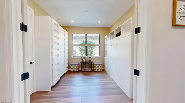 a hallway with wooden floor white walls and a window