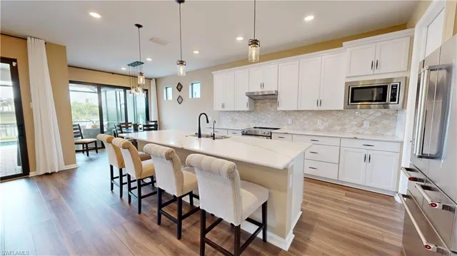 a kitchen with stainless steel appliances granite countertop a stove a refrigerator a kitchen island with a dining table and chairs