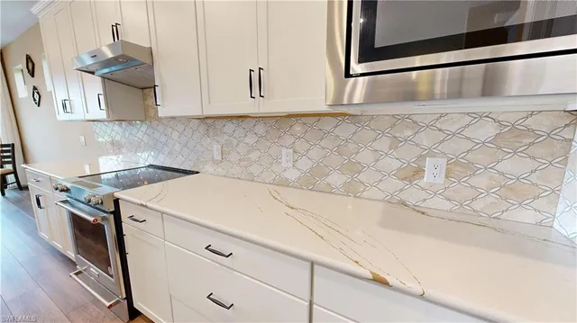 a kitchen with granite countertop white cabinets and white appliances