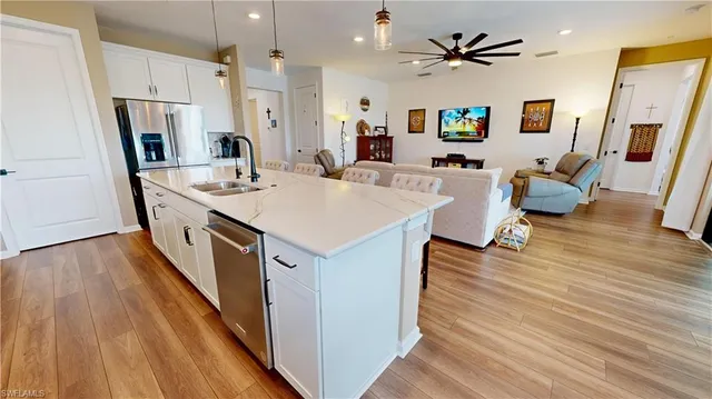 a living room with stainless steel appliances a dining table wooden floor and a couch