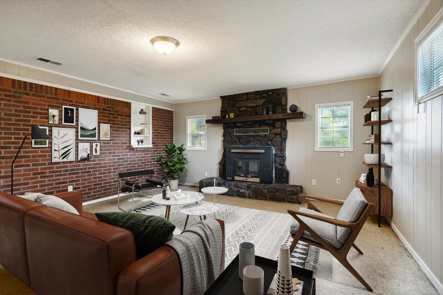 919 Stratford Road Memphis, TN 38122 - Photo 4 of 30 Carpeted living room with a stone fireplace, a textured ceiling, and brick wall