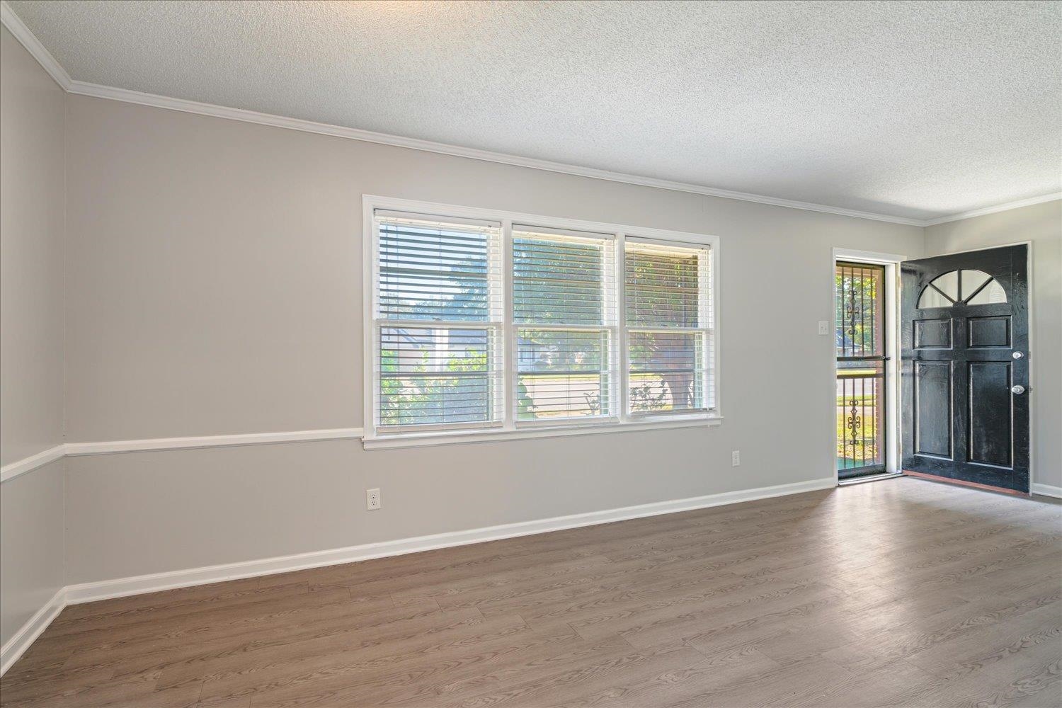 919 Stratford Road Memphis, TN 38122 - Photo 9 of 30 Spare room featuring crown molding, wood-type flooring, and a textured ceiling