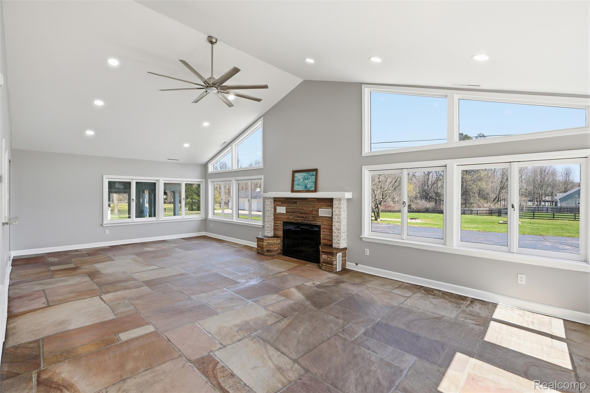 8636 Tindall Road Davisburg, MI 48350 - Photo 21 of 61 Unfurnished living room with a high ceiling, stone tile flooring, ceiling fan, recessed lighting, and a fireplace