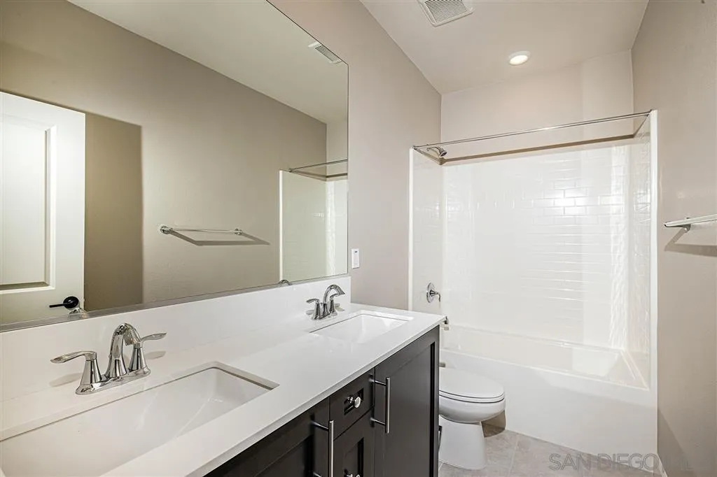 1182 Delpy View Point, Unit 106 Vista, CA 92084 - Photo 13 of 16 a bathroom with a double vanity sink toilet mirror and shower