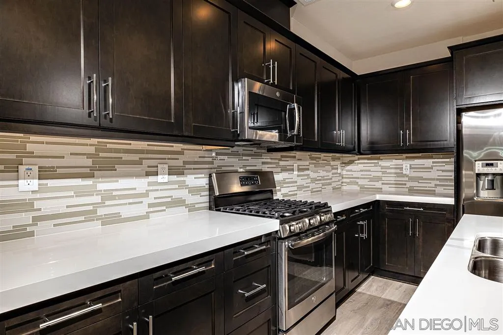 1182 Delpy View Point, Unit 106 Vista, CA 92084 - Photo 7 of 16 a kitchen with stainless steel appliances wooden cabinets and a stove top oven