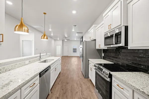 a large kitchen with stainless steel appliances granite countertop a stove a sink and a microwave