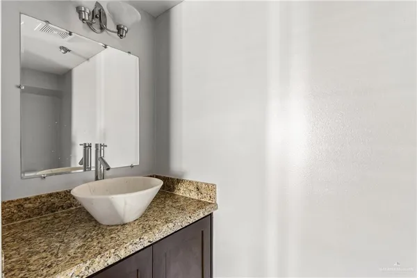 a bathroom with a granite countertop sink and a mirror