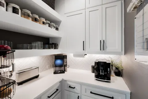 a kitchen with a sink a stove and white cabinets