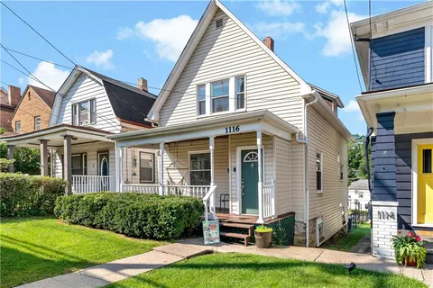 a front view of a house with a yard and potted plants