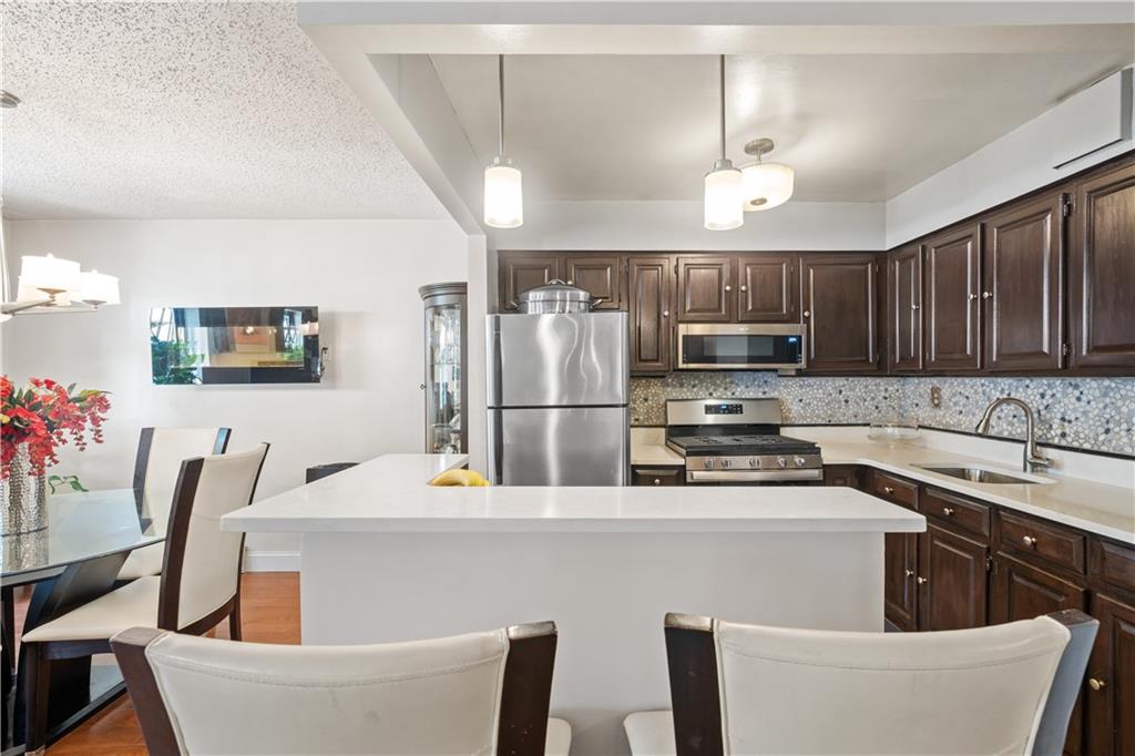 888 Gates Avenue Brooklyn, NY 11221 - Photo 5 of 18 a kitchen with stainless steel appliances a refrigerator a sink a stove a dining table and chairs
