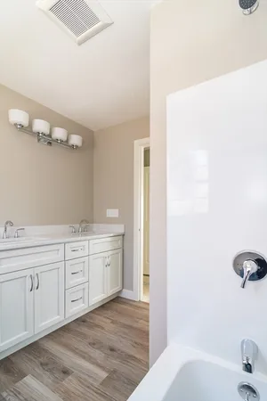 a spacious bathroom with a tub sink and mirror
