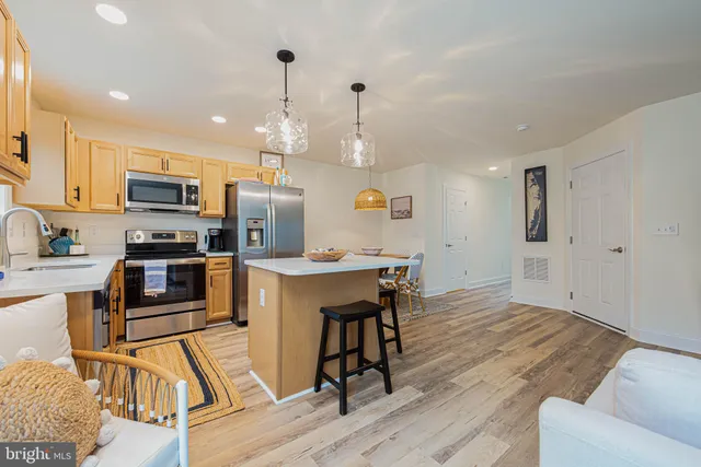 a kitchen with granite countertop a stove a sink a microwave a refrigerator and wooden floor