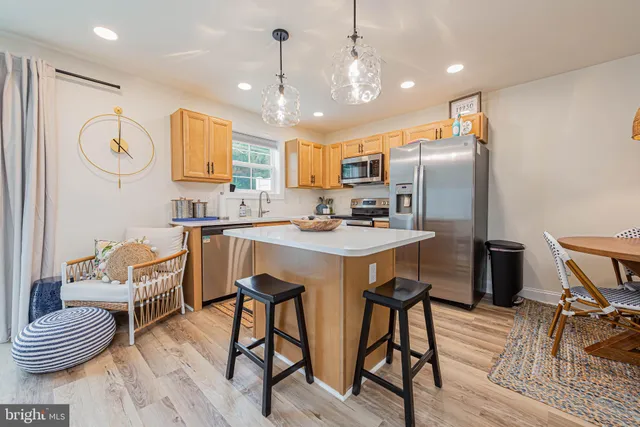 a kitchen with stainless steel appliances kitchen island granite countertop a sink refrigerator and cabinets