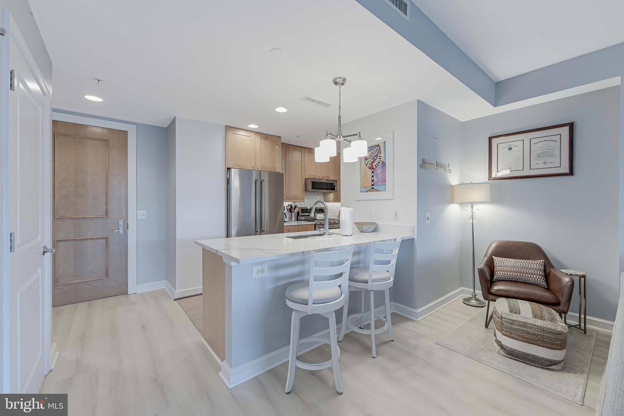 11990 Market Street, Unit 414 Reston, VA 20190 - Photo 13 of 52 a kitchen with kitchen island a dining table chairs a sink and a refrigerator