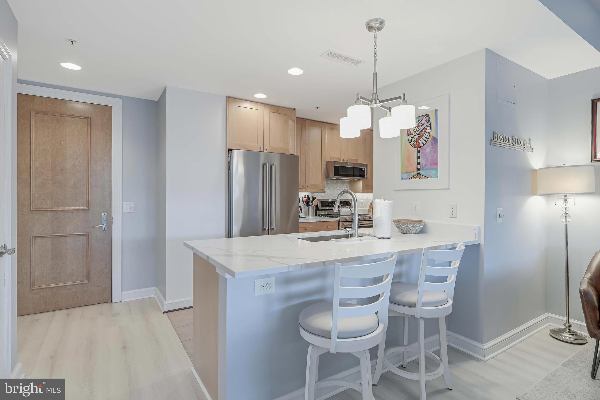 11990 Market Street, Unit 414 Reston, VA 20190 - Photo 14 of 52 a kitchen with stainless steel appliances a dining table chairs and refrigerator
