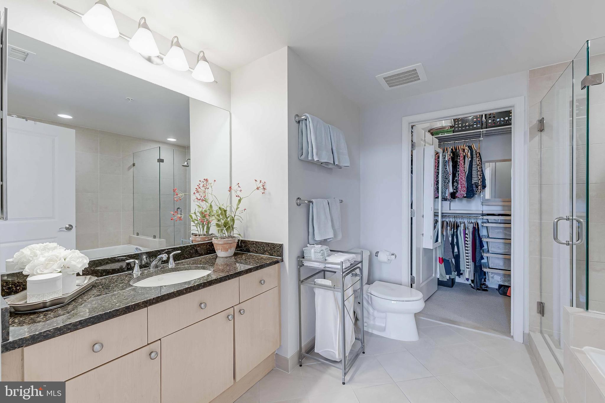 11990 Market Street, Unit 414 Reston, VA 20190 - Photo 32 of 52 a spacious bathroom with a granite countertop sink mirror and toilet