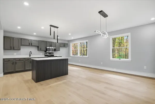 a kitchen with stainless steel appliances granite countertop a stove top oven a sink dishwasher and a refrigerator with wooden cabinets
