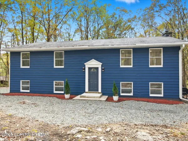 a front view of a house with a tree