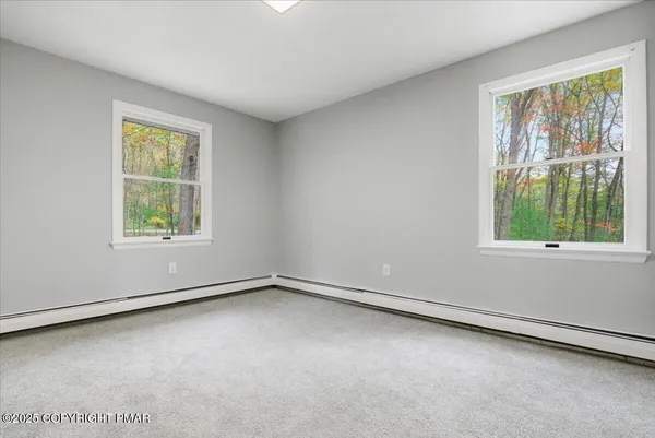an empty room with wooden floor and windows with curtains