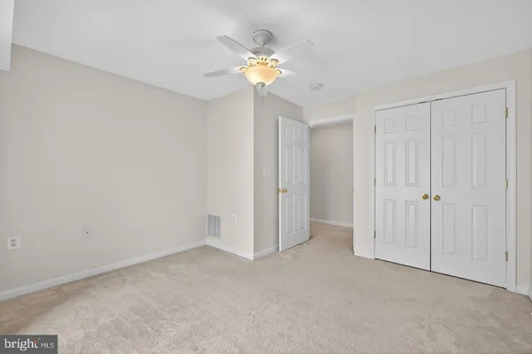 a view of an empty room and chandelier fan