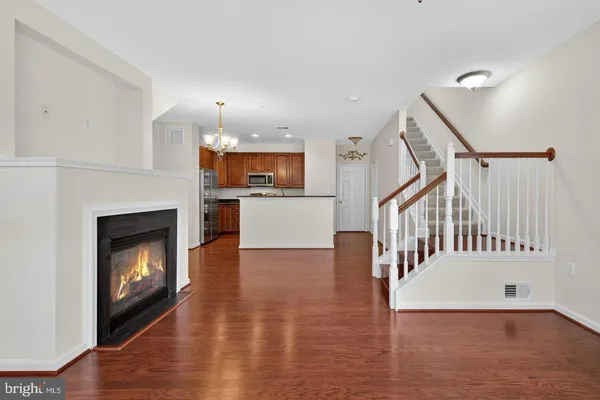 a view of an empty room with wooden floor fireplace and a window