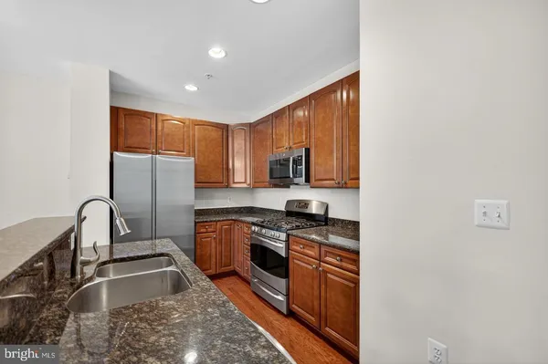 a kitchen with stainless steel appliances granite countertop a stove a sink and a refrigerator