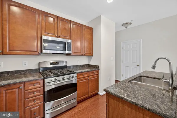 a kitchen with granite countertop wooden cabinets stainless steel appliances and a sink