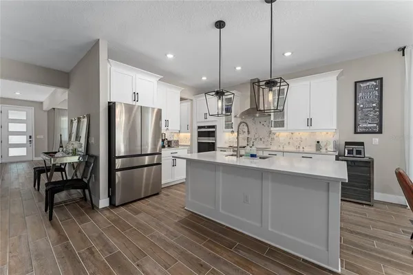 a kitchen with stainless steel appliances kitchen island granite countertop a refrigerator a sink dishwasher a oven and a dining table with wooden floor