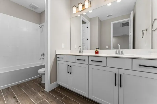 a bathroom with a double vanity sink a mirror and a bathtub