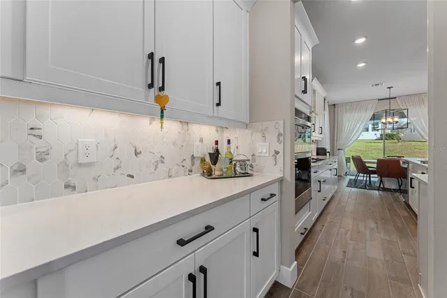 a kitchen with stainless steel appliances white cabinets and wooden floor