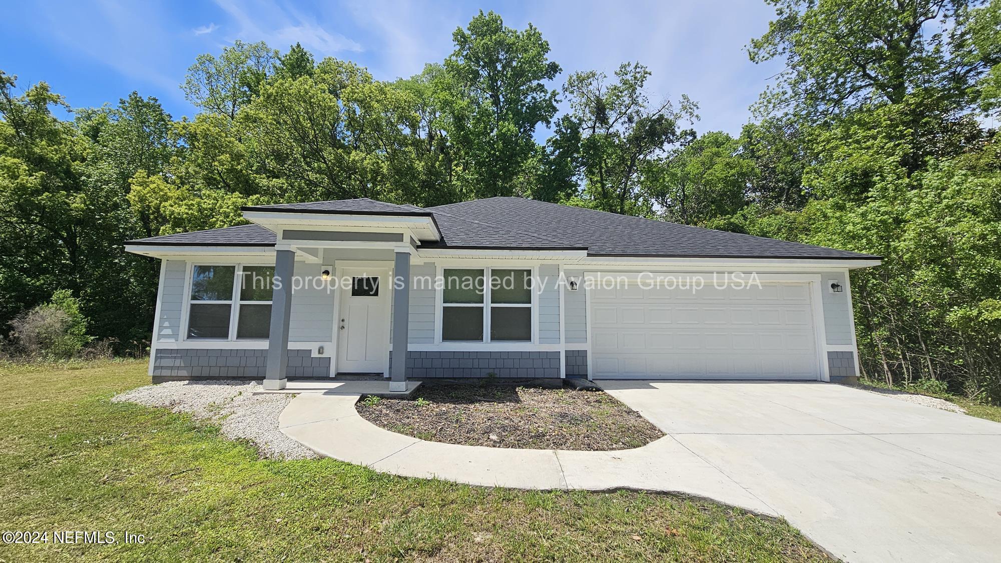 a front view of a house with a yard and potted plants