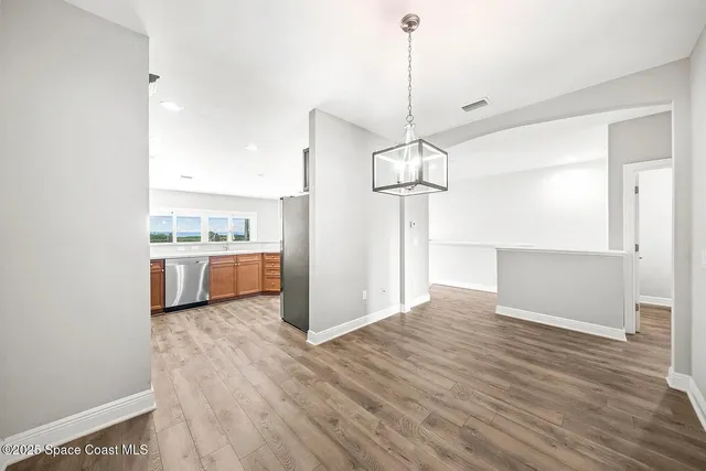 a view of a kitchen with a sink and dishwasher a refrigerator with wooden floor