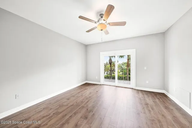 an empty room with wooden floor fan and windows