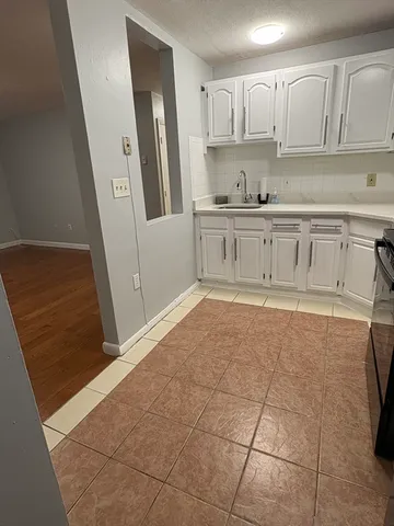 a kitchen with white cabinets and window